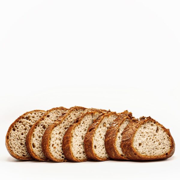 Pieza de pan de hogaza con ajo asado y un toque de tomillo, de corteza dorada y con una miga firme y jugosa a la vez que esponjosa sin gluten con corte.